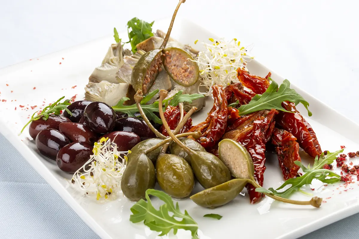 Kapern_mit_Stiel_Antipastiteller_Oliven_Sardellen_Tomaten_getrocknet_sprossen_rucola