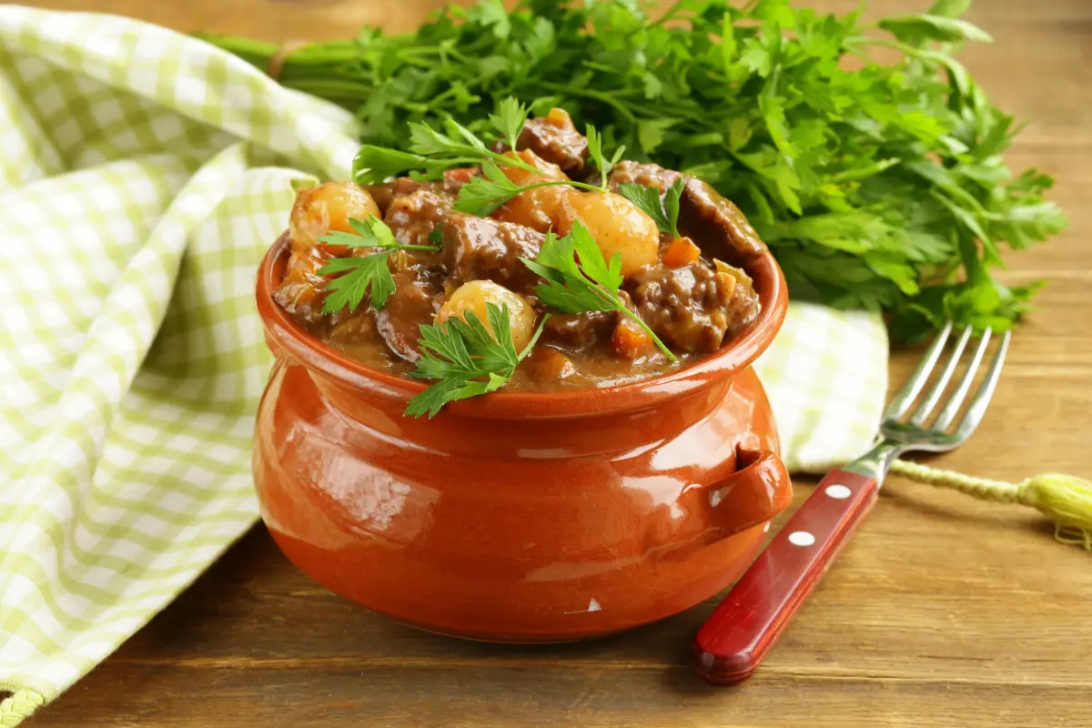 Gulasch_Eintopf_Tontopf_kraueter_holztisch_gabel